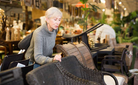 Mature woman choosing chair in furniture storeの写真素材