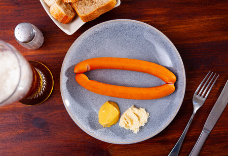 Pair of Vienna sausages with mustard and horseradish served with beerの写真素材