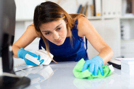 Mexican woman wearing uniform cleaning table in office