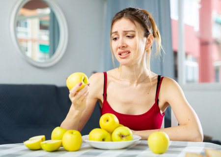 Portrait of diet tired young woman holding apples in her handsの写真素材