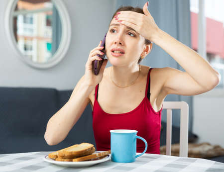 Caucasian woman having fever sitting and talking on phoneの写真素材