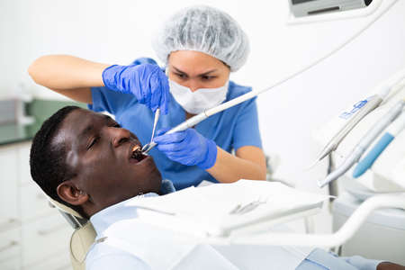 Woman stomatologist treating teeth to patient in dental officeの写真素材