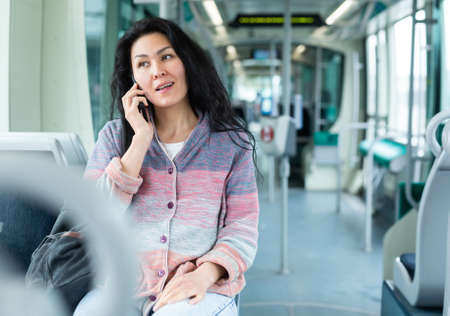 Woman using phone inside modern city tramの写真素材