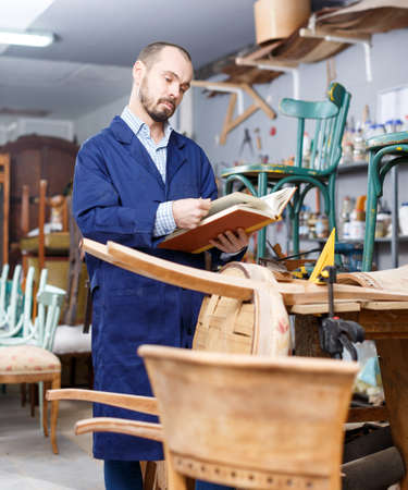 Craftsman looking at album in workshopの写真素材