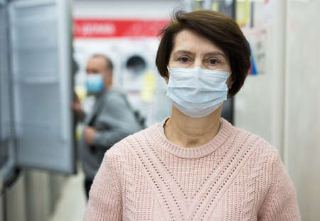 Portrait of a European woman in a protective mask in an electronics and home appliance storeの写真素材