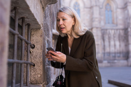 Mature woman is taking photos on her camera while journey through the city