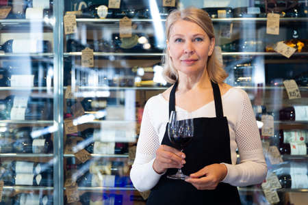 Female vintner proposing degustation of wineの写真素材