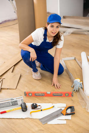 Woman construction worker setting wooden laminate board on floorの写真素材