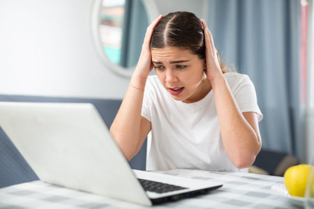 Girl with a headache complains to the doctor on the Internet using laptop