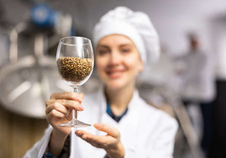 Woman brewer holding glass of malt seedsの写真素材