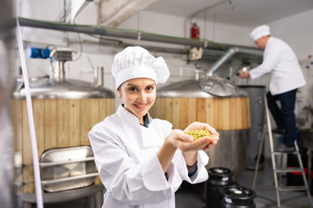 Smiling female brewmaster holding handful of pelletized hops