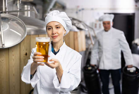 Portrait of woman brewmaster with glass of beerの写真素材
