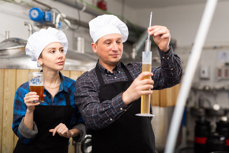 Woman and a man check the amount of alcohol in beer at private brewery