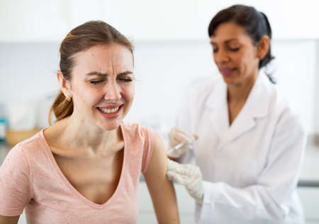 Woman client of medical clinic afraid of syringeの写真素材