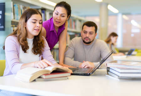 Group of people looking at laptop screen together and preparing for examの写真素材