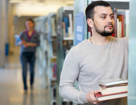 Portrait of man choosing books at libraryの写真素材