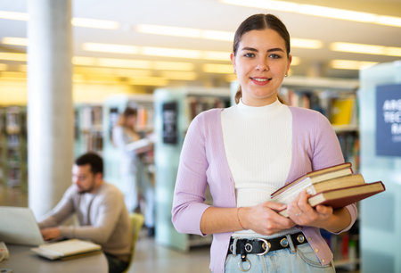 Portrait of a young woman in the library with textbooksの写真素材
