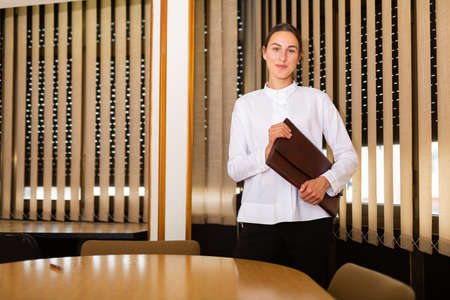 Young confident woman stands near a round table in the conference roomの写真素材