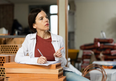 Female foreman keeps records of building materials in room being repaired