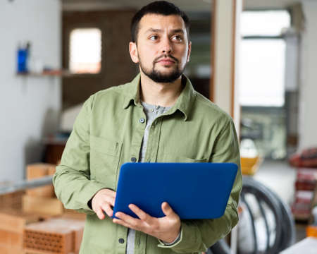 Civil engineer monitors the process of capital repairs on a laptopの写真素材