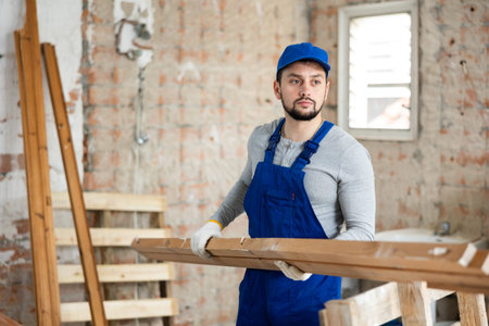 Professional builder holds wooden bars in his hands