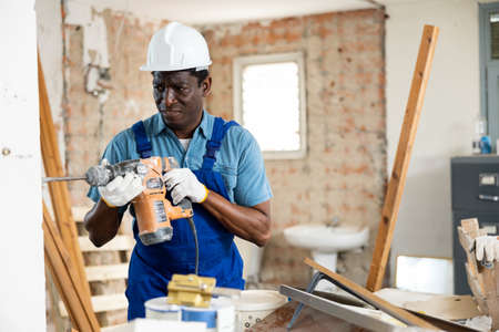 Confused inexperienced builder working with pneumatic demolition hammerの写真素材