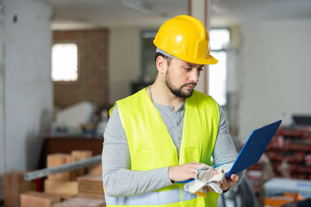 Builder checks the house repair plan on a laptopの写真素材