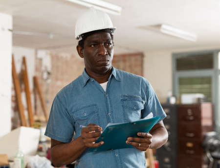 Strict building inspector standing with papers at construction siteの写真素材