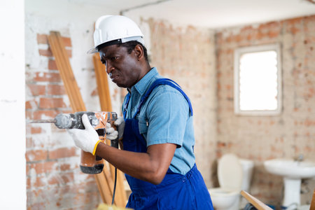 Focused african american builder working with pneumatic jackhammer