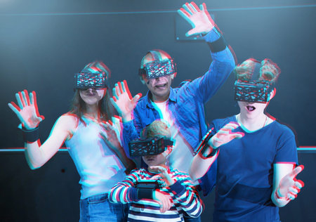 Family with children playfully poses in virtual reality glasses
