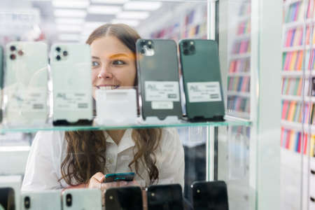 Woman looking at smart phones at the multimedia storeの写真素材