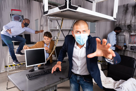 Team of friends in protective masks is looking for a way out of quest room