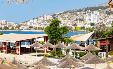 Thatched beach umbrellas on background of Sarande cityscapeの写真素材