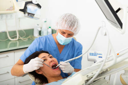 Man doctor treats patient teeth using boron machine in clinicの写真素材