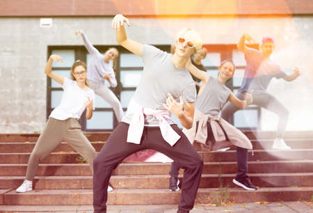 Happy smiling teenagers practicing vigorous hip hop movements at streetの写真素材
