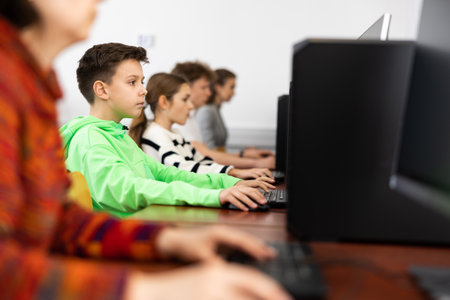 Positive female teacher tells a teenager how to work on computerの写真素材
