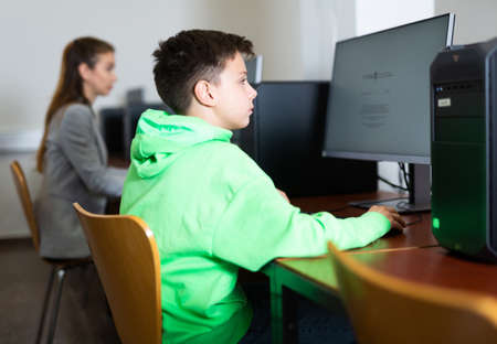 Preteen boy learning basics of programming in computer collegeの写真素材