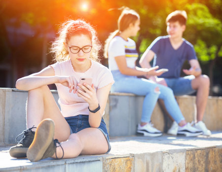 Teen girl carried away with smartphone outdoorの写真素材