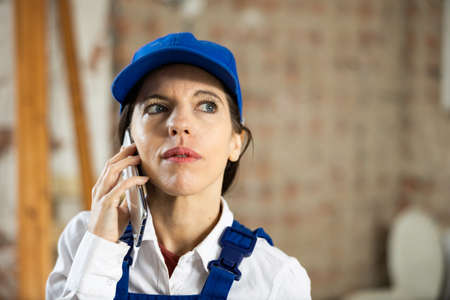 Female foreman talking on phone in building under constructionの写真素材