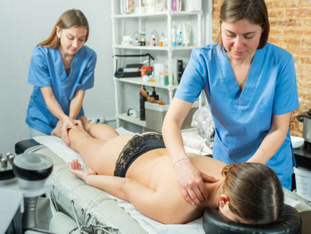 Two masseuses do a massage to a client girlの写真素材