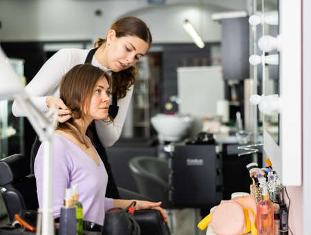 Interested female client discussing haircut with professional hairdresserの写真素材