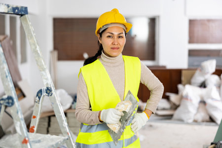 Portrait of female house painter with tools in renovated roomの写真素材