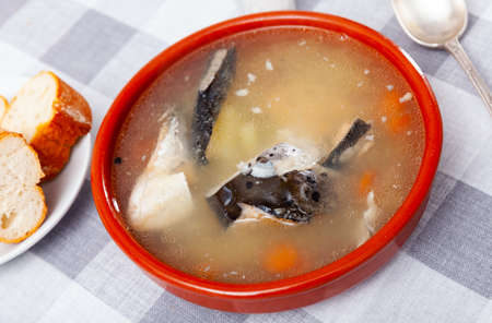 Salmon head soup with potatoes and carrots in clay bowlの写真素材