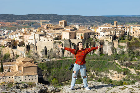 Woman tourist with a camera, against the background of the city of Cuenca, stands and enjoys freedom