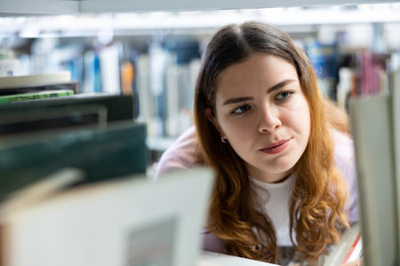 Portrait of woman choosing books at libraryの写真素材