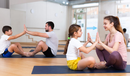 Children and parents sitting back to back on yoga mats