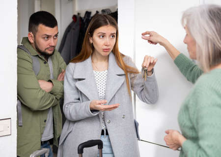 Dissatisfied owner receiving keys from married couple tenantsの写真素材