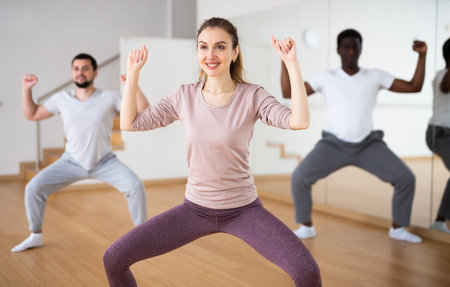 Woman dancing aerobic dance with men in studio
