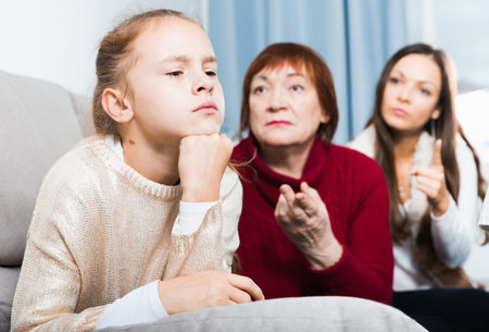 Frustrated girl while mother and grandmother berating her