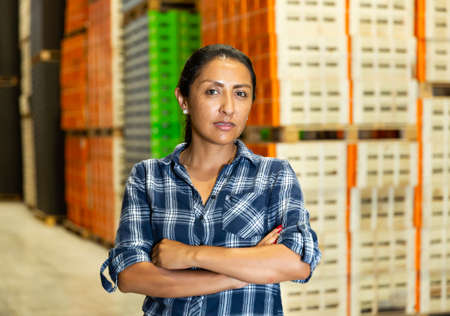 Portrait of worker with arms crossed standing in warehouseの写真素材